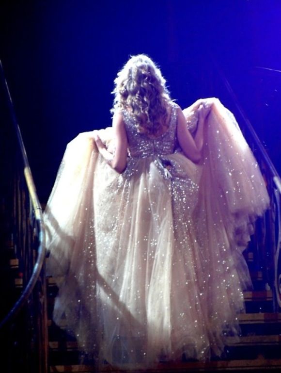 a woman in a white dress is sitting on some stairs with her hands behind her back