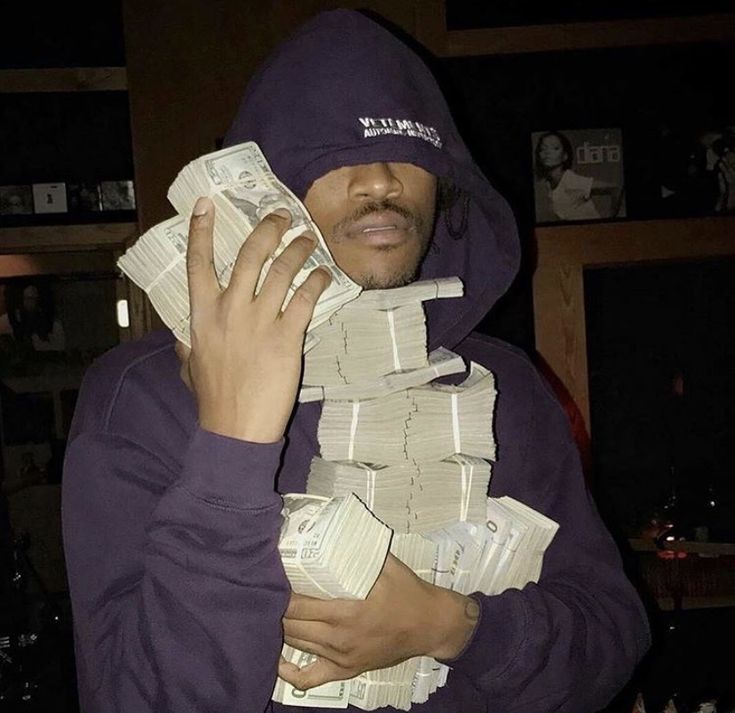 a man in a purple hoodie holding stacks of money