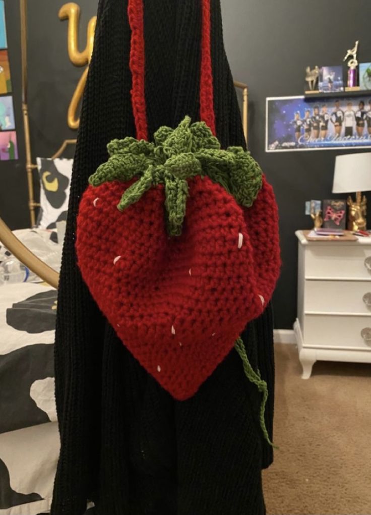 a crocheted strawberry bag hanging from a hook