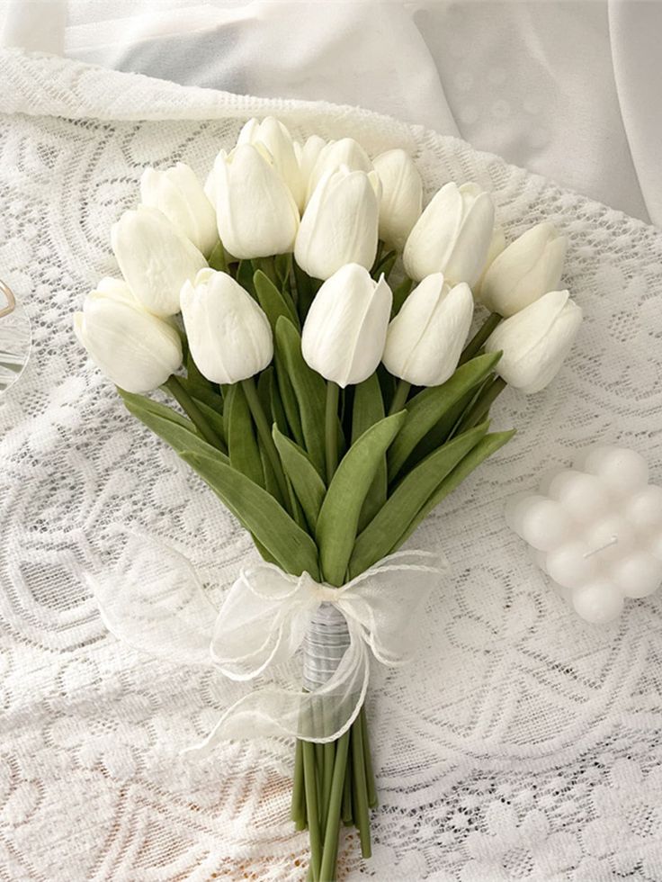 a bouquet of white tulips on a lace doily