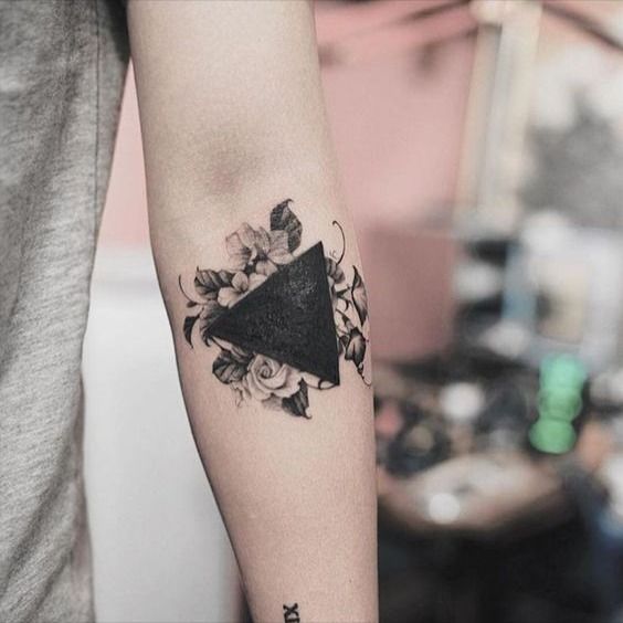 a black triangle tattoo on the left forearm and right arm, with flowers around it