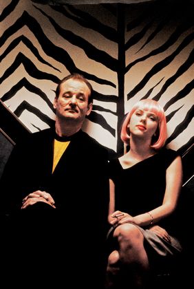 a man and woman sitting next to each other in front of a zebra print wall