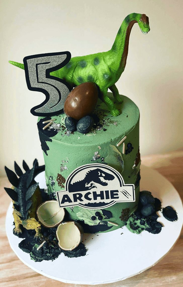 a birthday cake with a green dinosaur on top and the number five in the middle