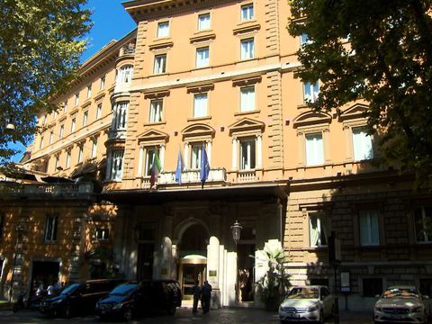 a large building with cars parked in front of it on a city street next to trees