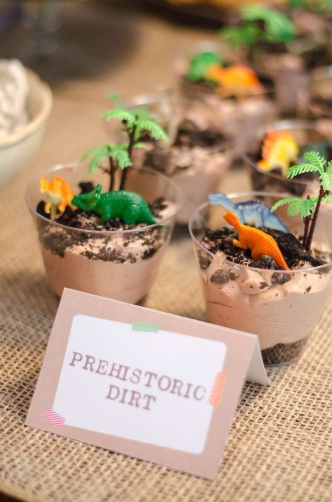 small plastic dinosaurs in dirt pots on a table with a sign that says, prehistoriic dit