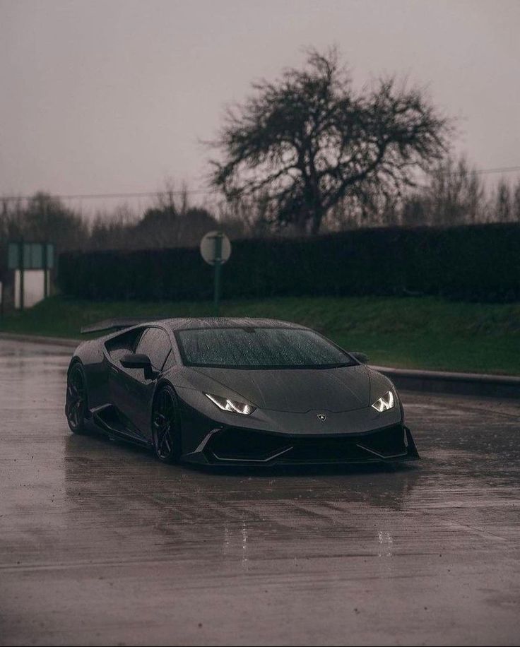 a black sports car driving down a wet road