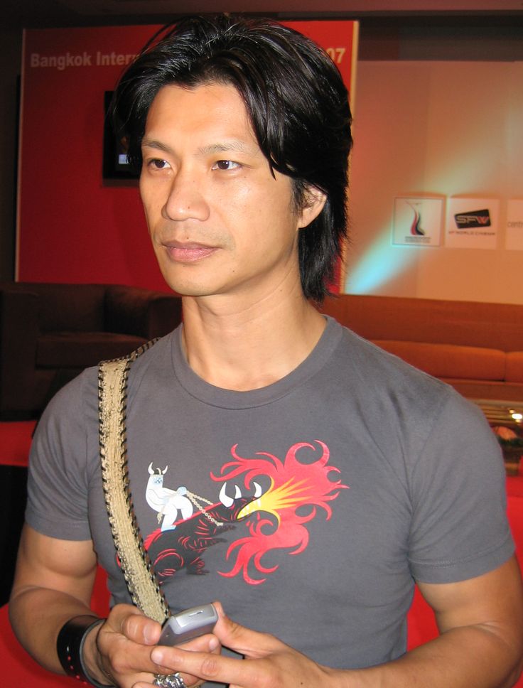 a man holding a cell phone in his right hand and wearing a gray t - shirt