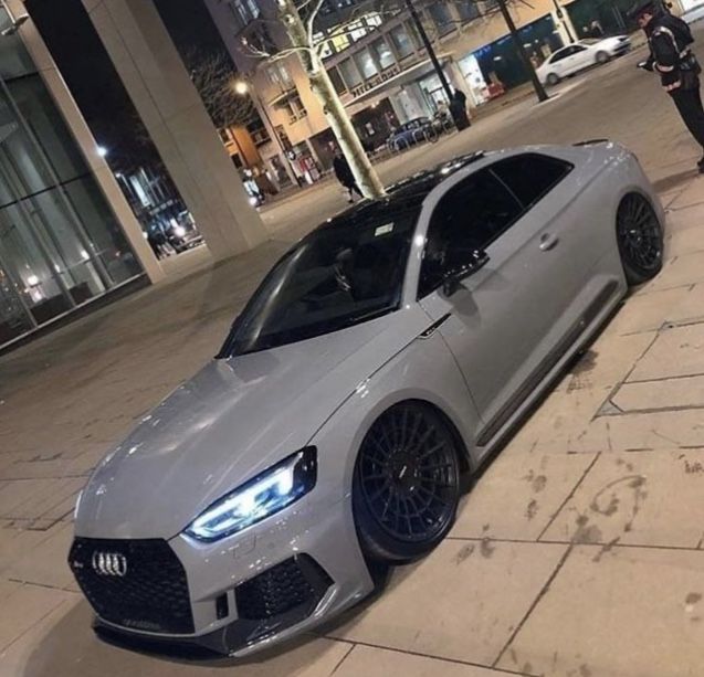 a grey car parked on the side of a street next to a police officer standing in front of it