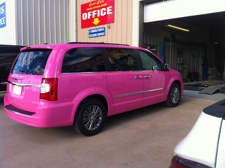 a bright pink van parked in front of a building with an office sign on it