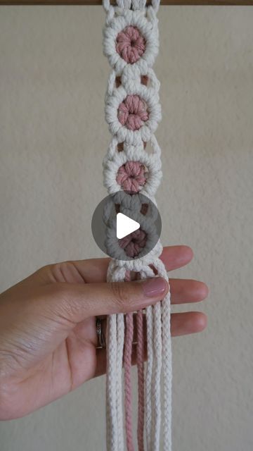 someone is holding up a crocheted bracelet with buttons and yarns on it