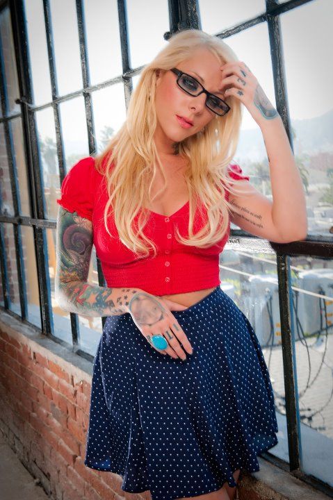 a woman in a red top and blue polka dot skirt is posing for the camera