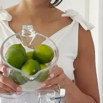 a woman holding a blender filled with limes