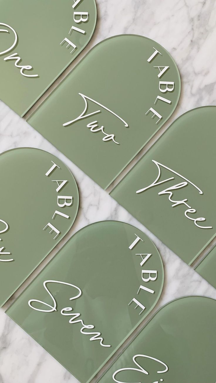 four green glass name plates with white writing on them and the names of each plate