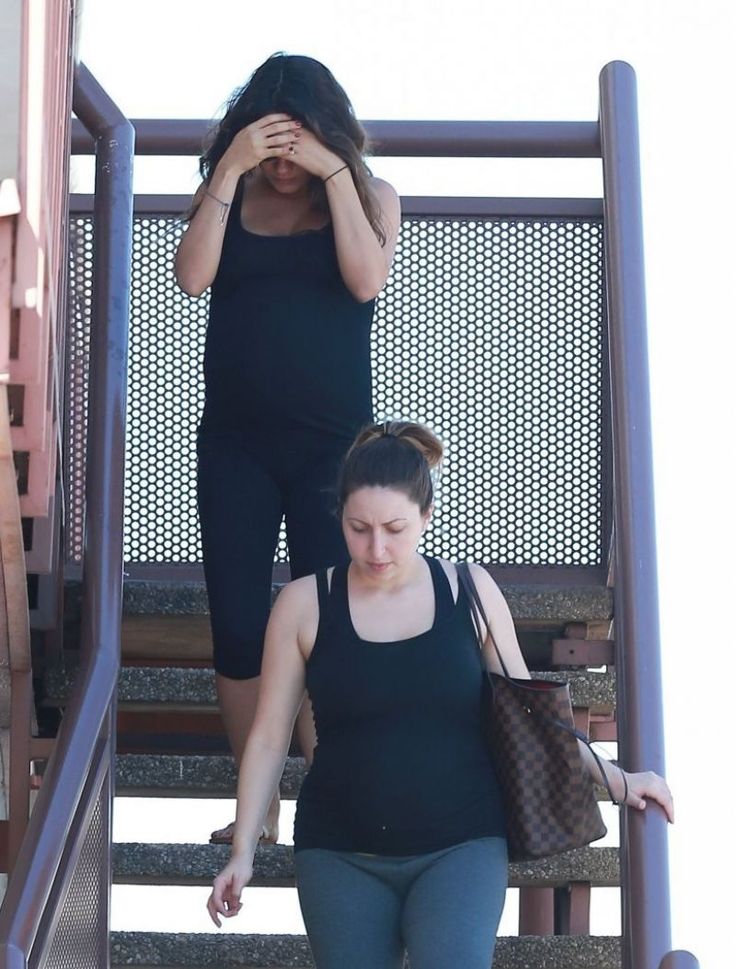 two women walking up some stairs with one holding her hand on her head and the other covering her eyes