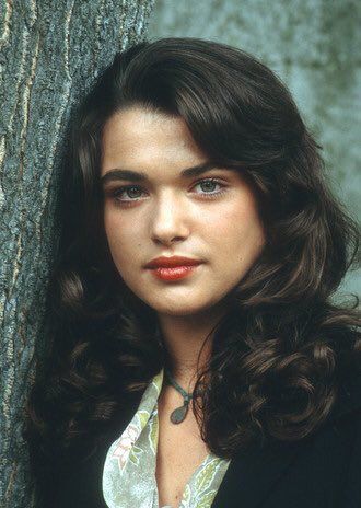 a woman leaning against a tree wearing a black jacket