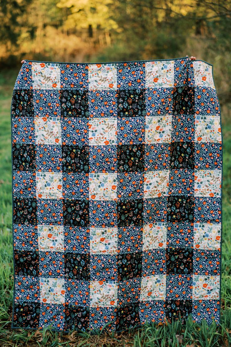 a black and white checkered quilt sitting on top of a green grass covered field