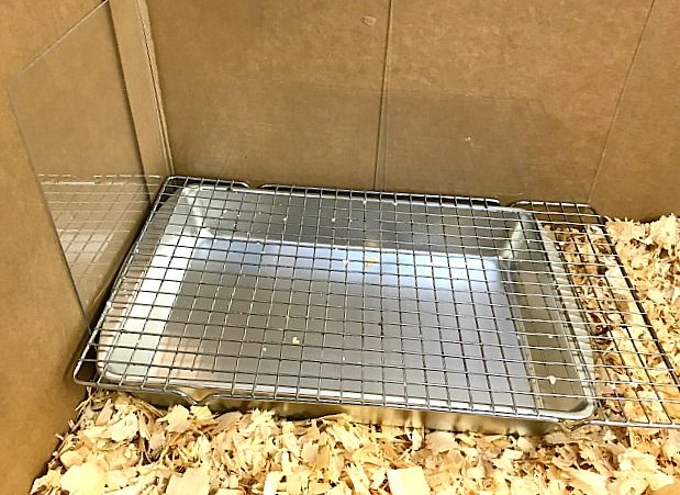 a metal tray filled with wood chips on top of a floor