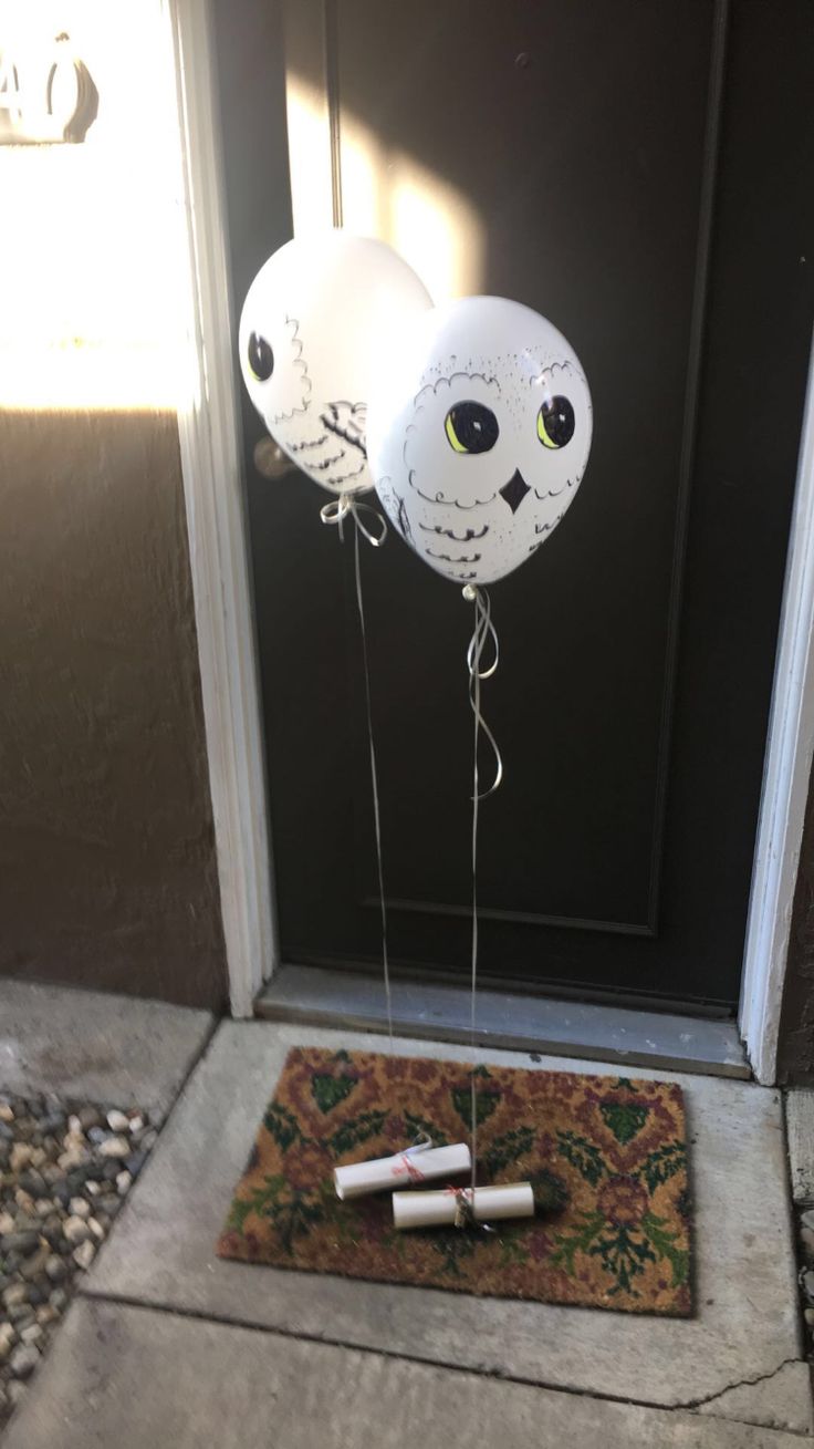 two white balloons with faces on them are attached to the front door, while another balloon is in the air