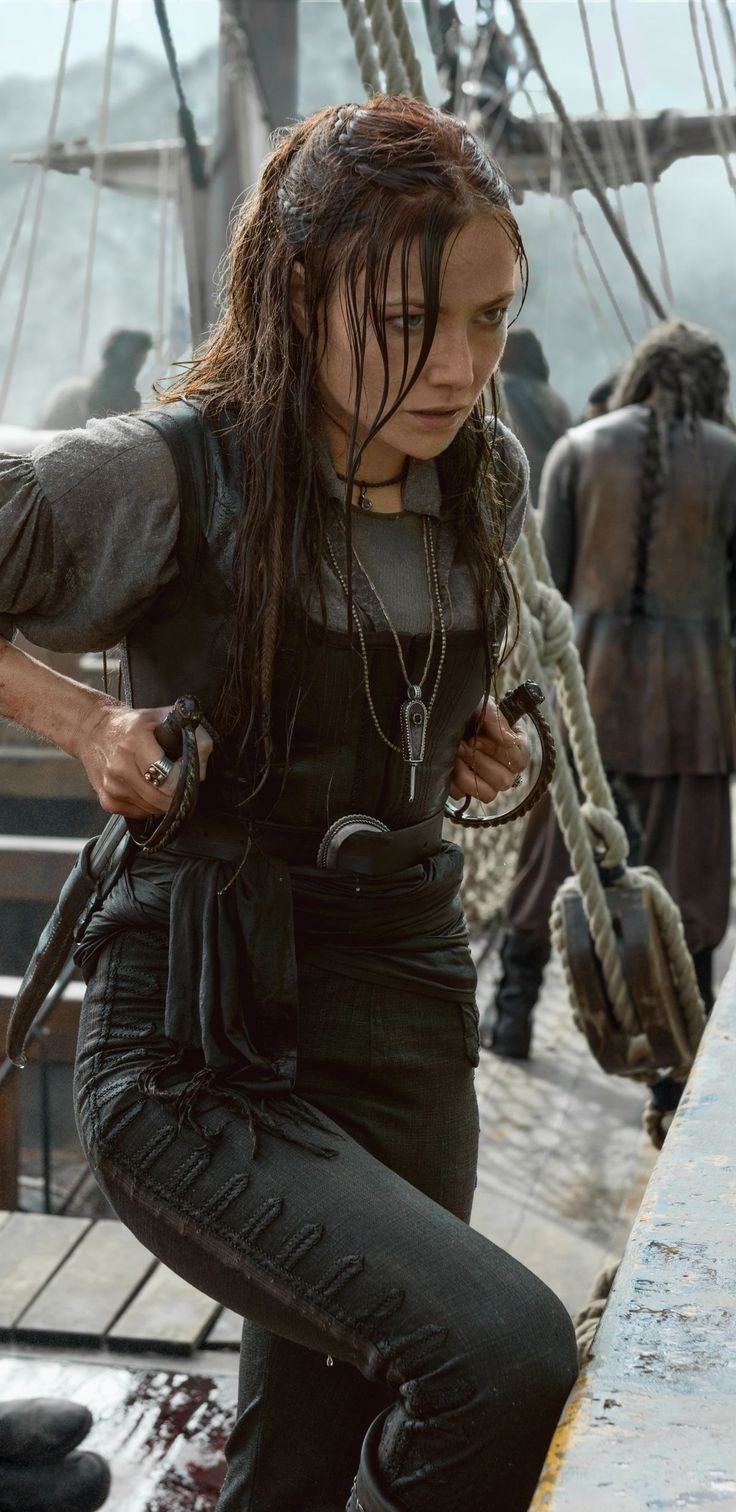 a woman standing on top of a boat next to another person with long hair and dreadlocks