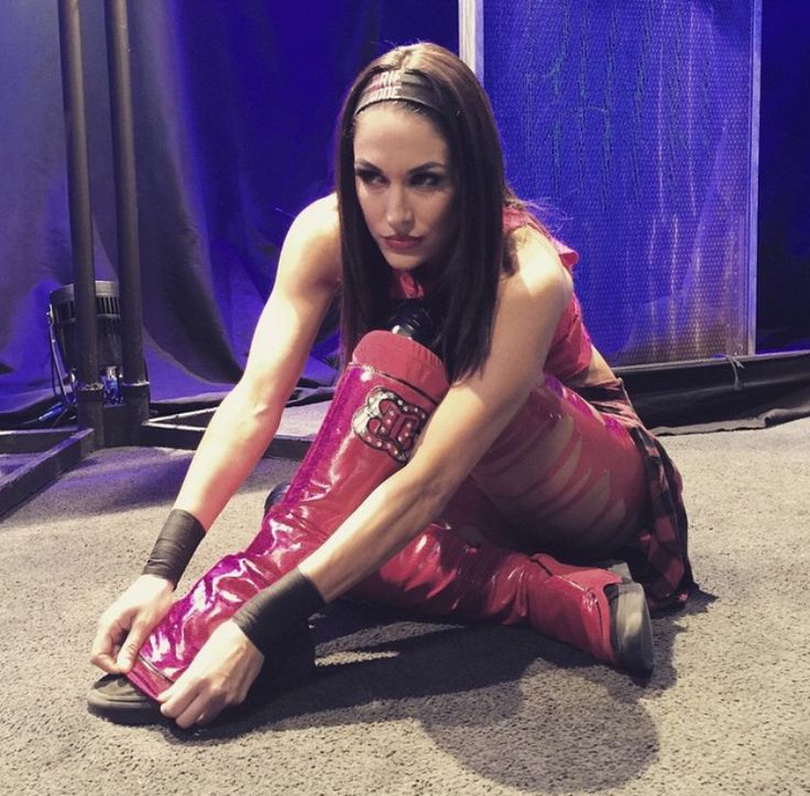 a woman sitting on the ground wearing red boots and holding her leg in one hand