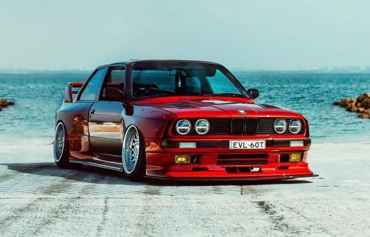 a red car parked in front of the ocean