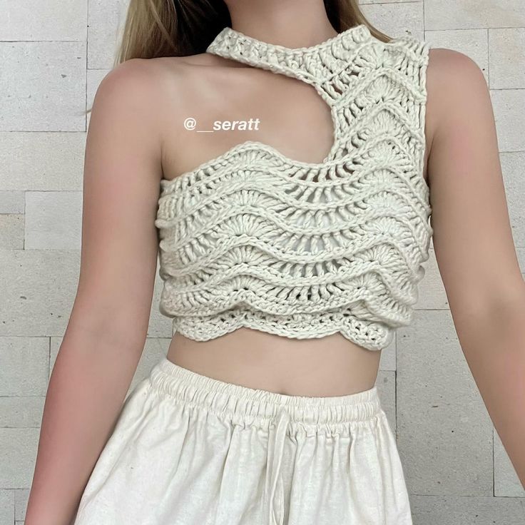 a woman with long blonde hair wearing a white crochet crop top and shorts