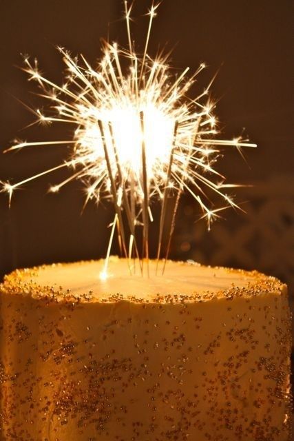 a sparkler on top of a cake with gold sprinkles