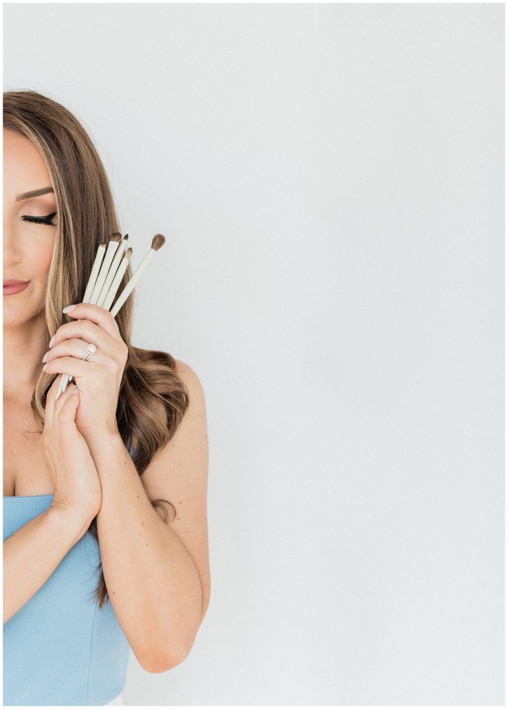 a woman in a blue dress is holding three brushes