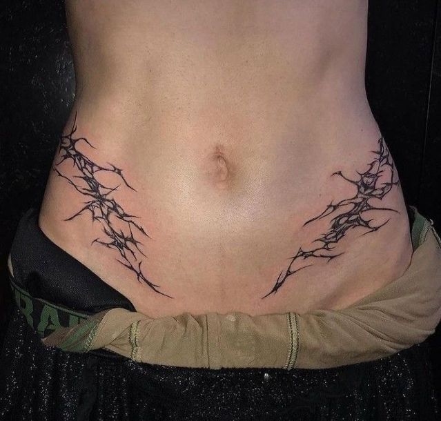 a woman's stomach with barbed wire tattoo on her side and the bottom part of her body