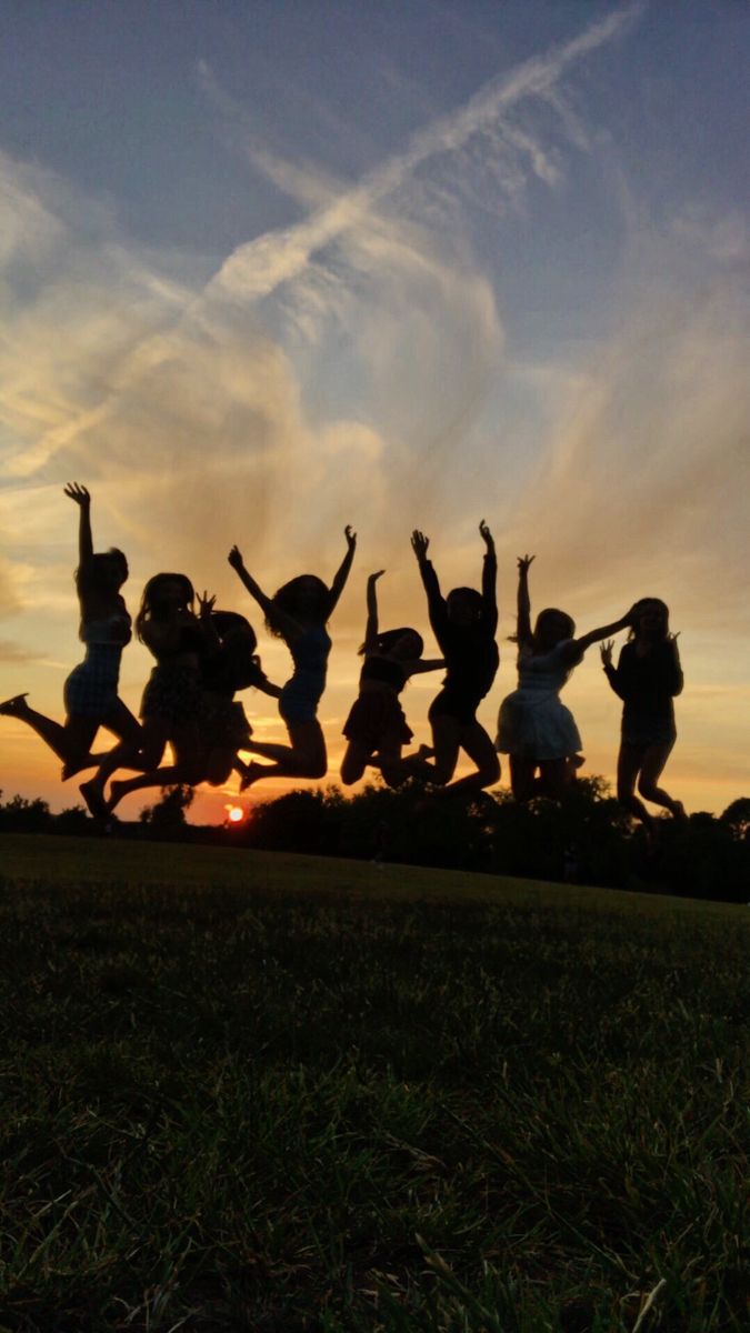 a group of people jumping in the air at sunset