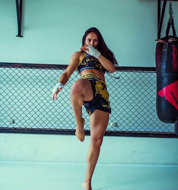 a woman kicking a punching bag in a gym