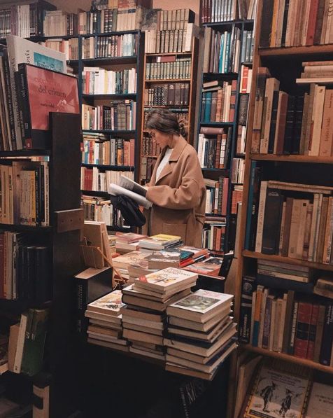 a person standing in front of a book shelf filled with books and looking at it