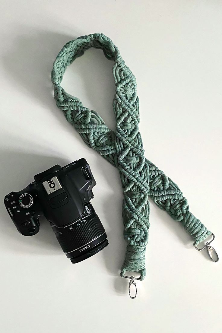 a camera and a green rope on a white surface with the strap attached to it