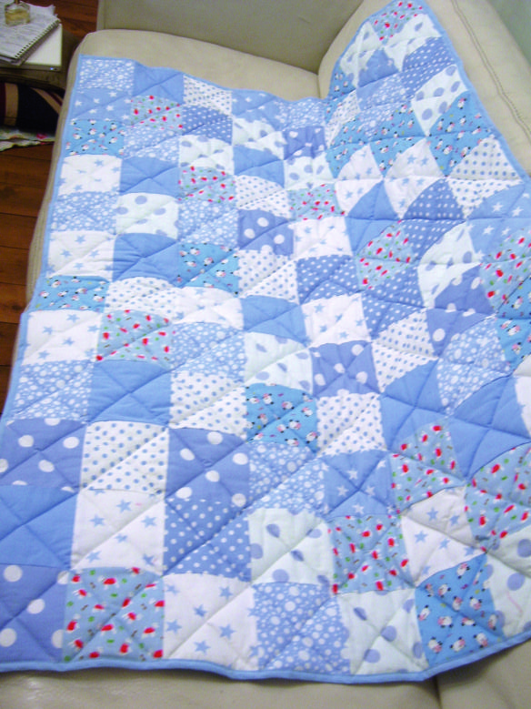 a blue and white quilt sitting on top of a couch