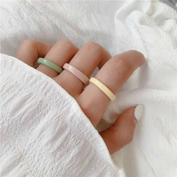 three different colored rings on someone's hand with white towel in the foreground