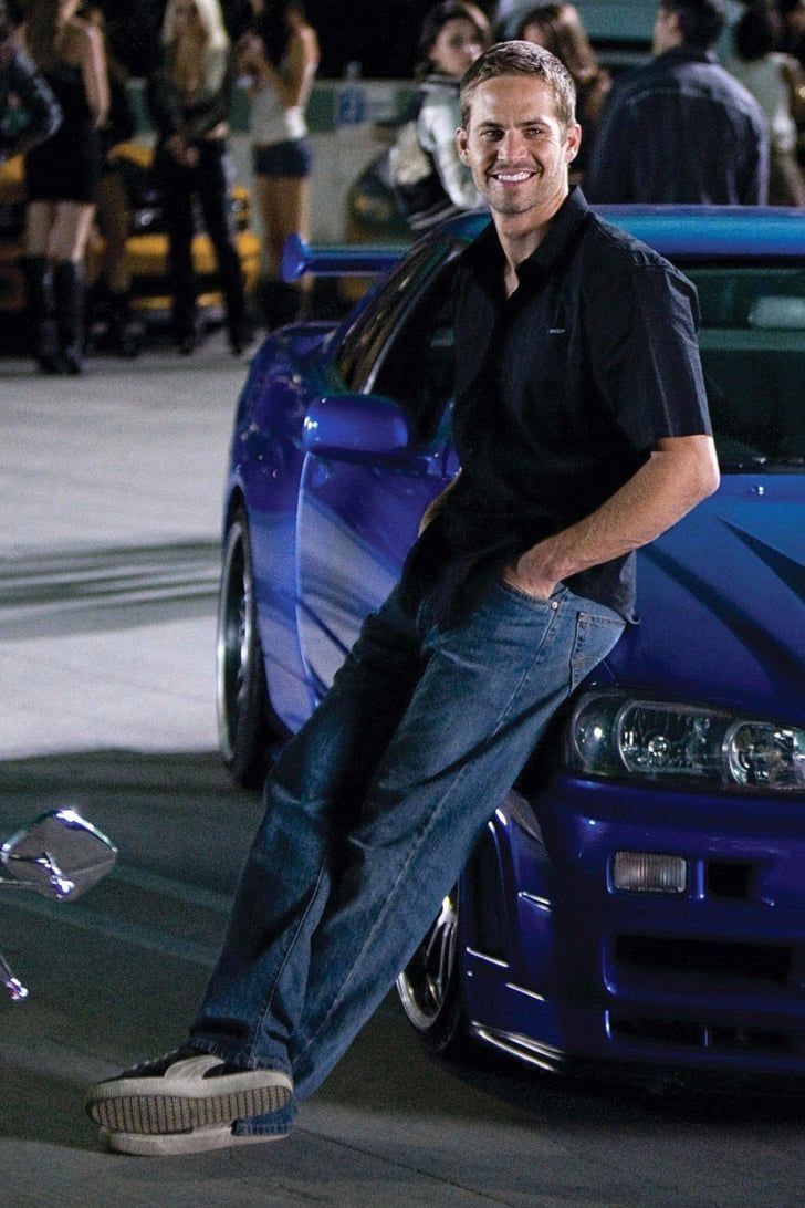 a man leaning on the hood of a blue car