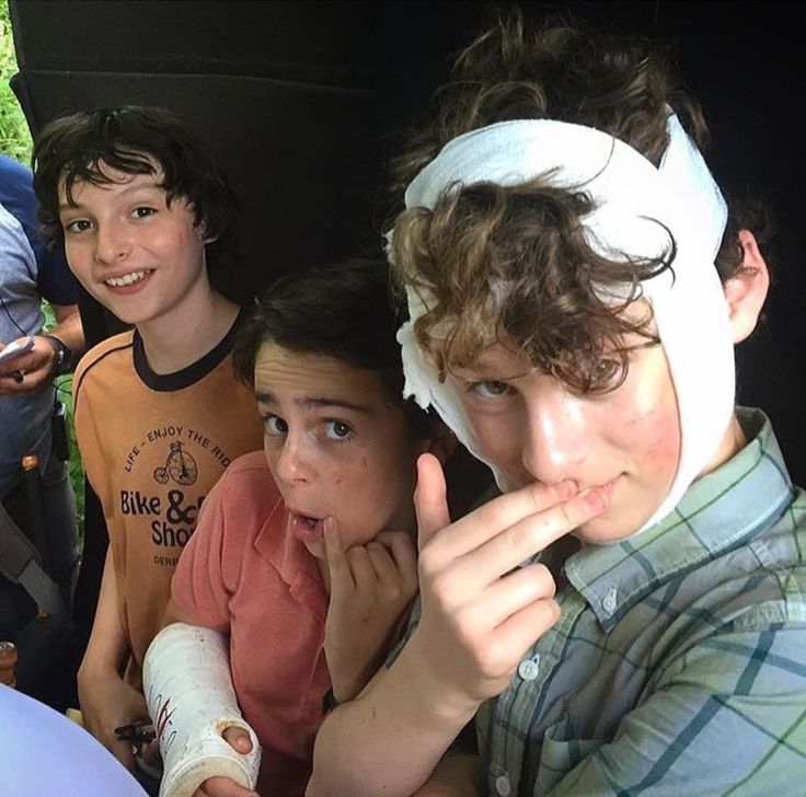 four children sitting in the back of a car with bandages on their heads and one child holding his thumb up