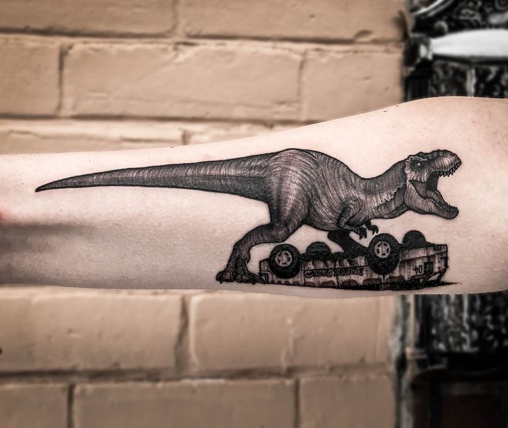 a man's arm with a black and white tattoo of a dinosaur riding a tractor