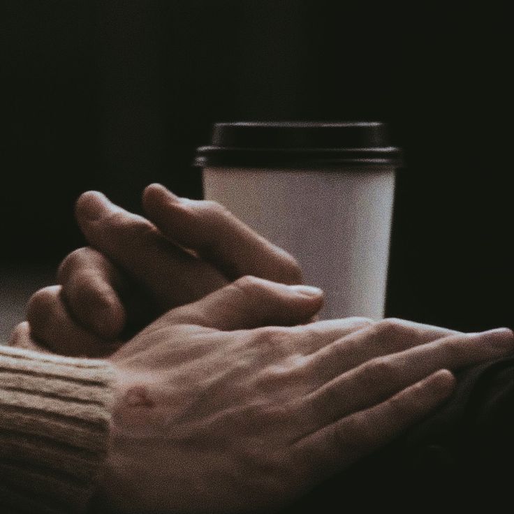 two hands holding each other over a coffee cup