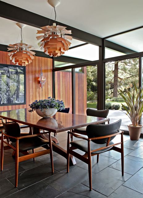 an old photo of a dining room table and chairs in front of a wooden paneled wall