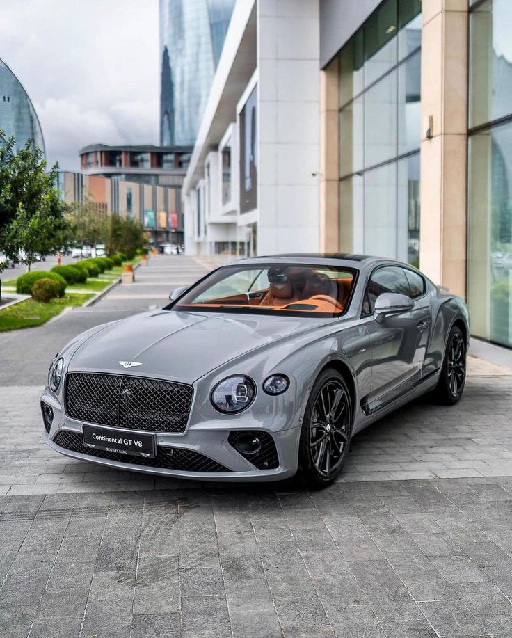a silver bentley parked in front of a building