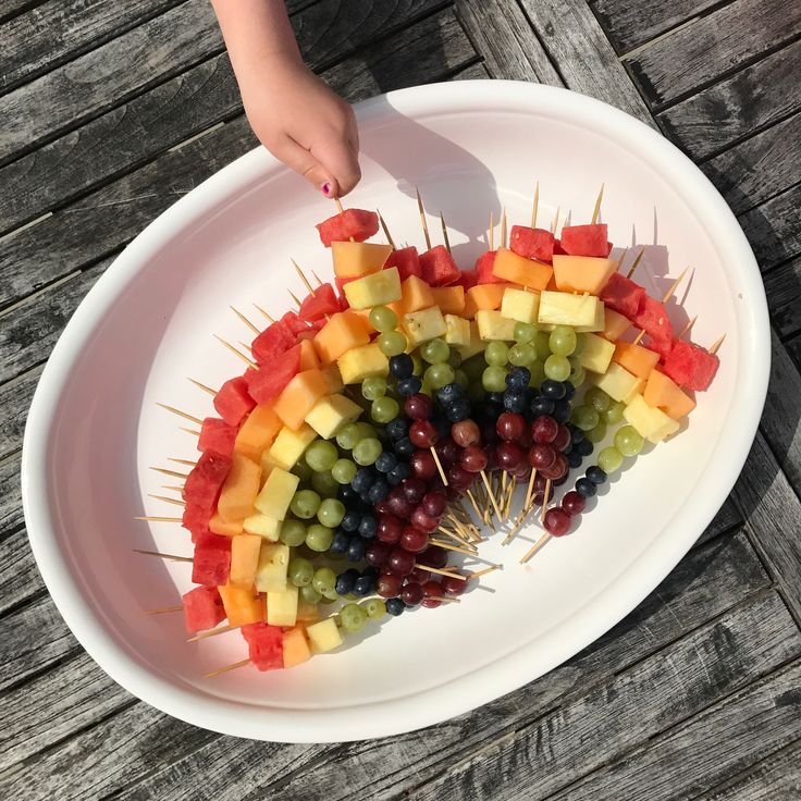 a white plate topped with fruit and skewers on top of a wooden table