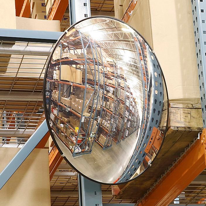 a large round mirror hanging from the side of a metal pole in a warehouse or building