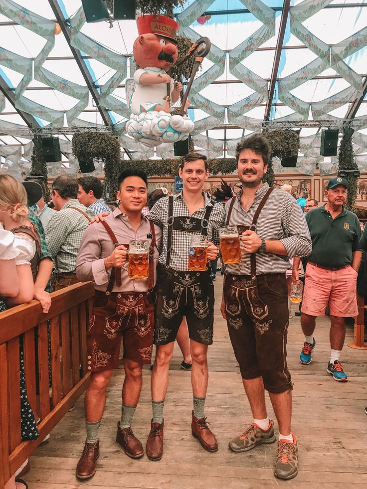 two men standing next to each other holding beer glasses