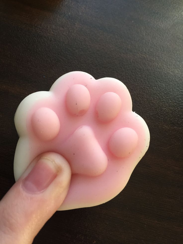 a hand is holding a pink bear paw mold