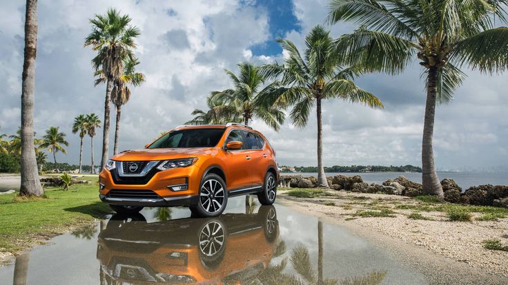 an orange nissan suv is parked in front of some palm trees and the water reflecting it's surface