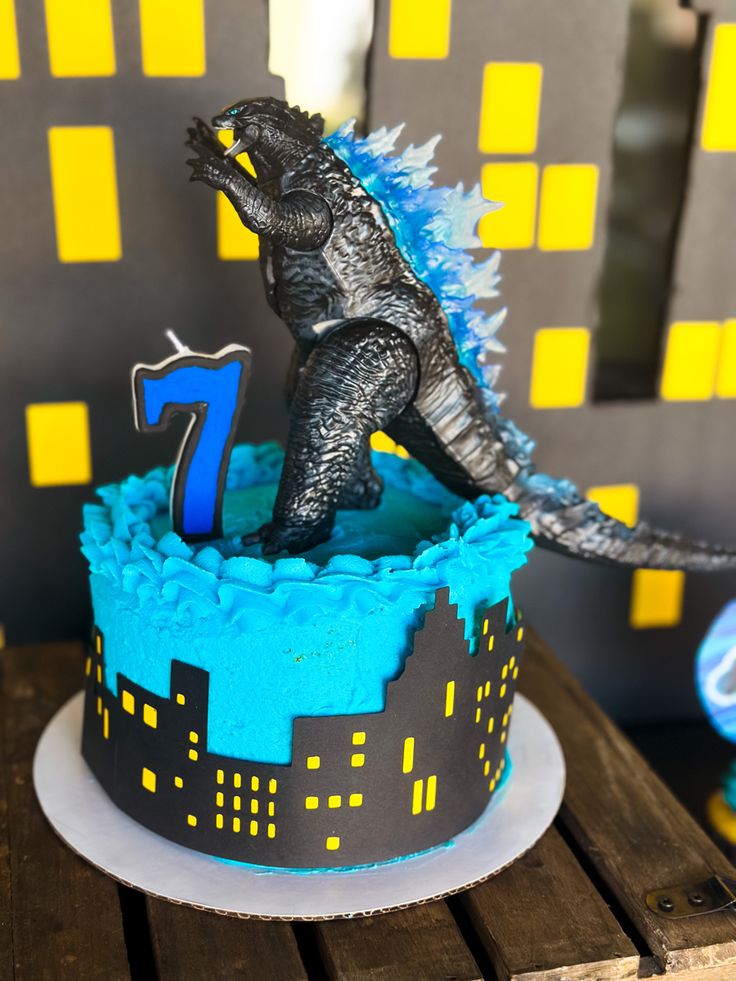 a birthday cake with a godzilla topper and number seven on it's side