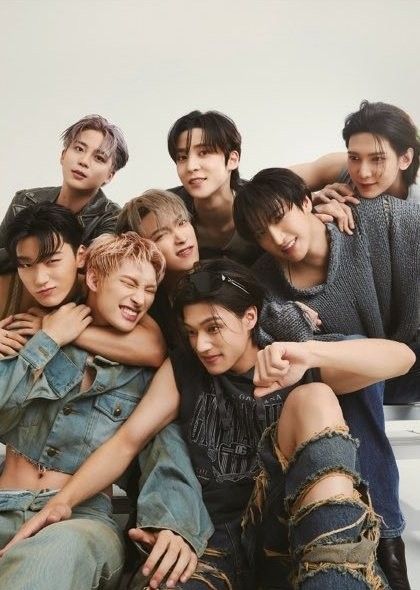 a group of young men sitting next to each other in front of a white wall