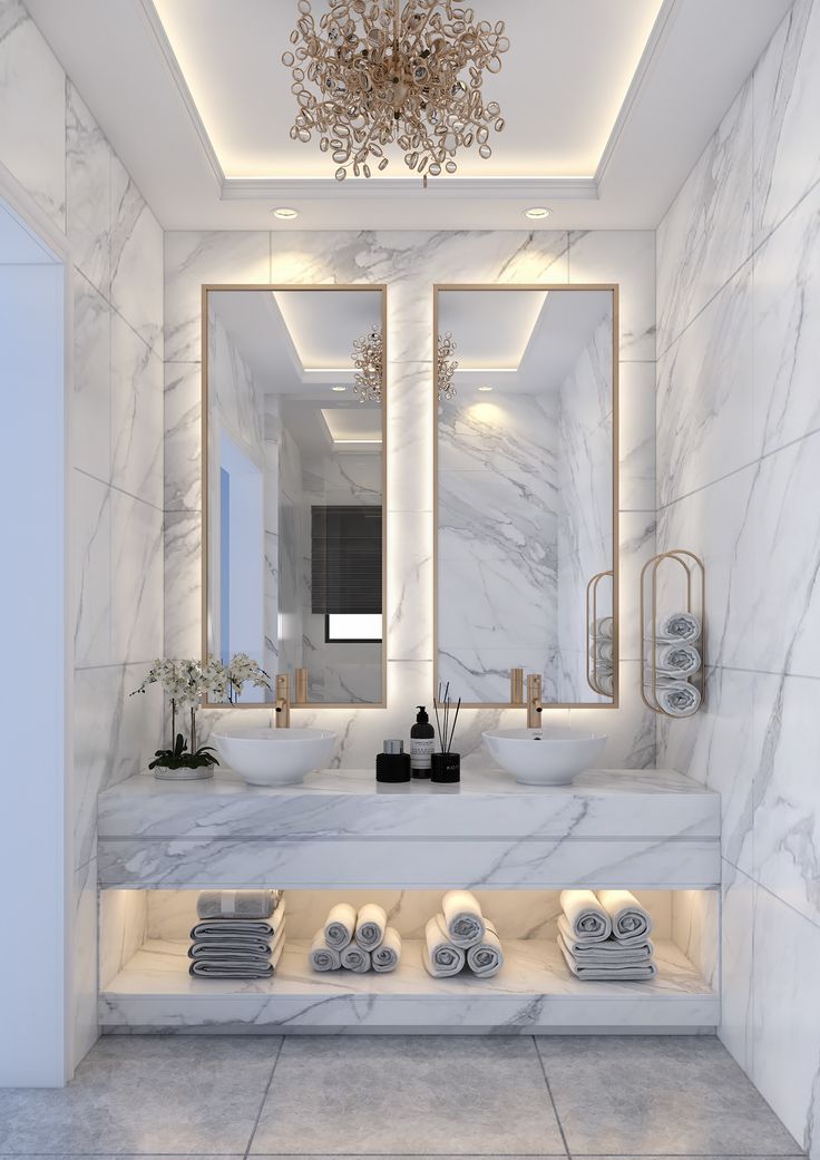 a bathroom with marble walls and flooring, lights on the ceiling above the sinks
