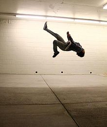 a man flying through the air while riding a skateboard in a parking lot at night